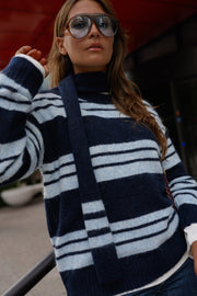 Pull doux avec écharpe porté par une femme, vue rapprochée, main dans les cheveux, lunettes