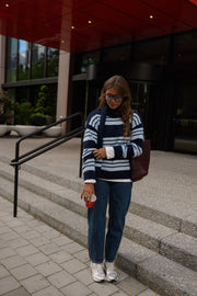 Pull doux avec écharpe porté par une femme, silhouette entière, sur des marches