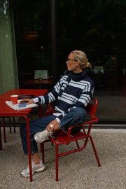 Pull doux avec écharpe porté par une femme, assise, à une table rouge