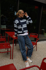 Pull doux avec écharpe porté par une femme, silhouette entière, lunettes de soleil, près de chaises rouges