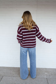 Pull doux à col revers porté par une femme, vue de dos, mur blanc, cheveux blonds
