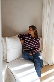 Pull doux à col revers porté par une femme, assise, canapé blanc, coussins