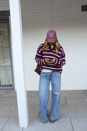 Pull doux à col revers porté par une femme, vue de face, casquette mauve, poteau