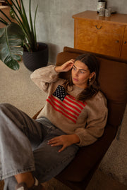 Pull à drapeau col rond camel porté par une femme, assise, fauteuil, jean
