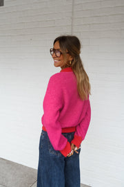 Pull à bords contrastés porté par une femme, vue de profil, mur blanc, lunettes