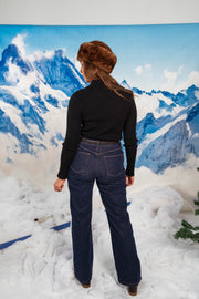 Pull moulant à col revers noir porté par une femme, vue de dos, bonnet en fourrure, jean