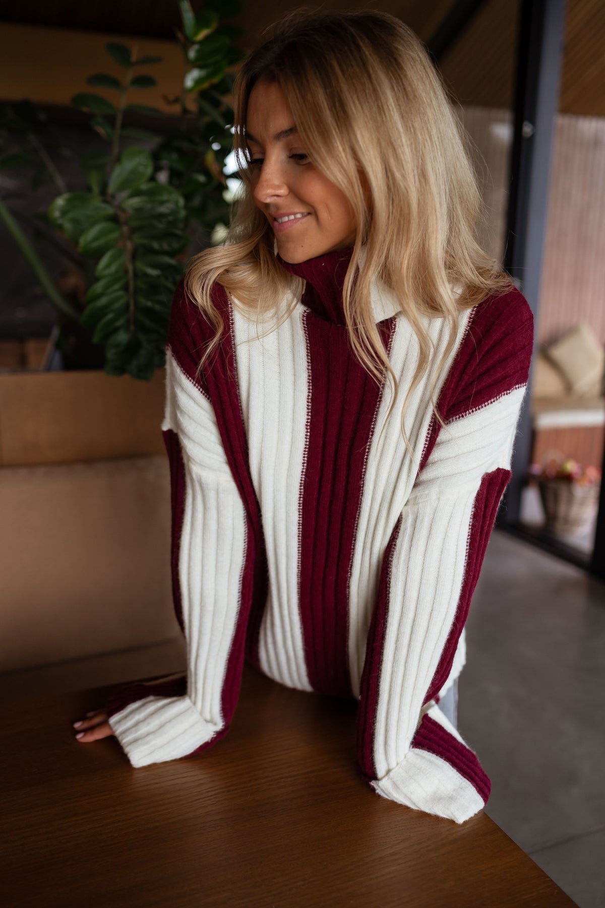 Pull rayé à col roulé porté par une femme, vue rapprochée, rayures bordeaux, sourire