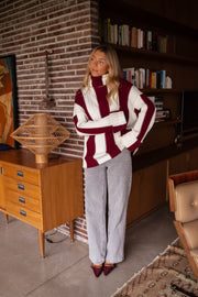Pull rayé à col roulé porté par une femme, silhouette entière, jupe en cuir, rayures