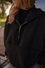 Pull ample zippé à capuche noir porté par une femme, vue rapprochée, col zippé, capuche