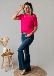 Pull baby alpaga manches courtes porté par une femme, vue de trois-quarts, main sur la tête, jean flare