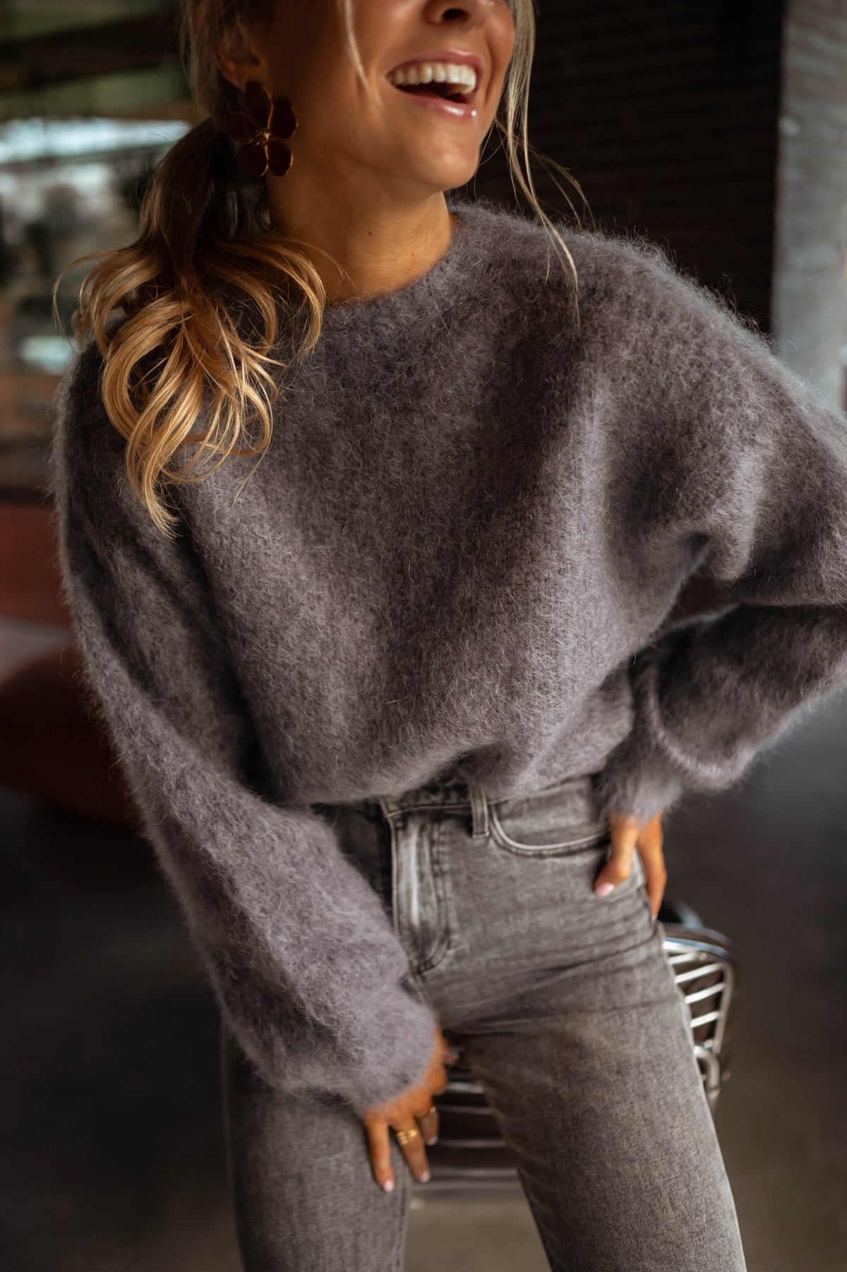 Pull doux et ample gris porté par une femme, vue rapprochée, sourire, jean gris