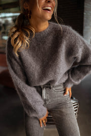 Pull doux et ample gris porté par une femme, vue rapprochée, sourire, jean gris