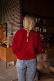 Pull doux légèrement ample bordeaux porté par une femme, vue de dos, tresse, jean
