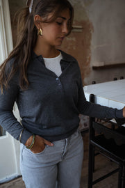 Pull à col revers boutonné gris porté par une femme, vue de face, fenêtre, jean clair