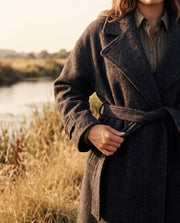 Manteau oversize en laine porté par une femme, vue rapprochée, ceinture nouée, boutons