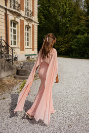 Robe longue moulante drapée portée par une femme, vue de dos, gravier, cape