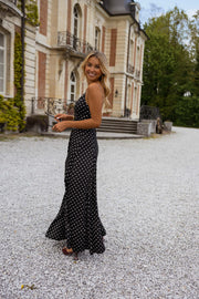 Robe longue à bretelles réglables portée par une femme, silhouette entière, façade, haie