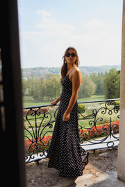 Robe longue à bretelles réglables portée par une femme, silhouette entière, balcon, fleurs rouges