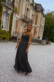 Robe longue à bretelles réglables portée par une femme, silhouette entière, façade, gravier