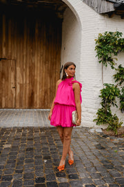 Robe courte à jupe boule portée par une femme, silhouette entière, porte en bois, robe rose