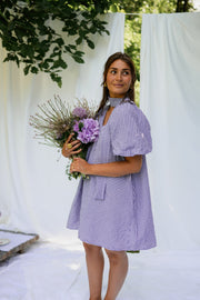 Robe fluide courte col V portée par une femme, silhouette entière, bouquet, drapés