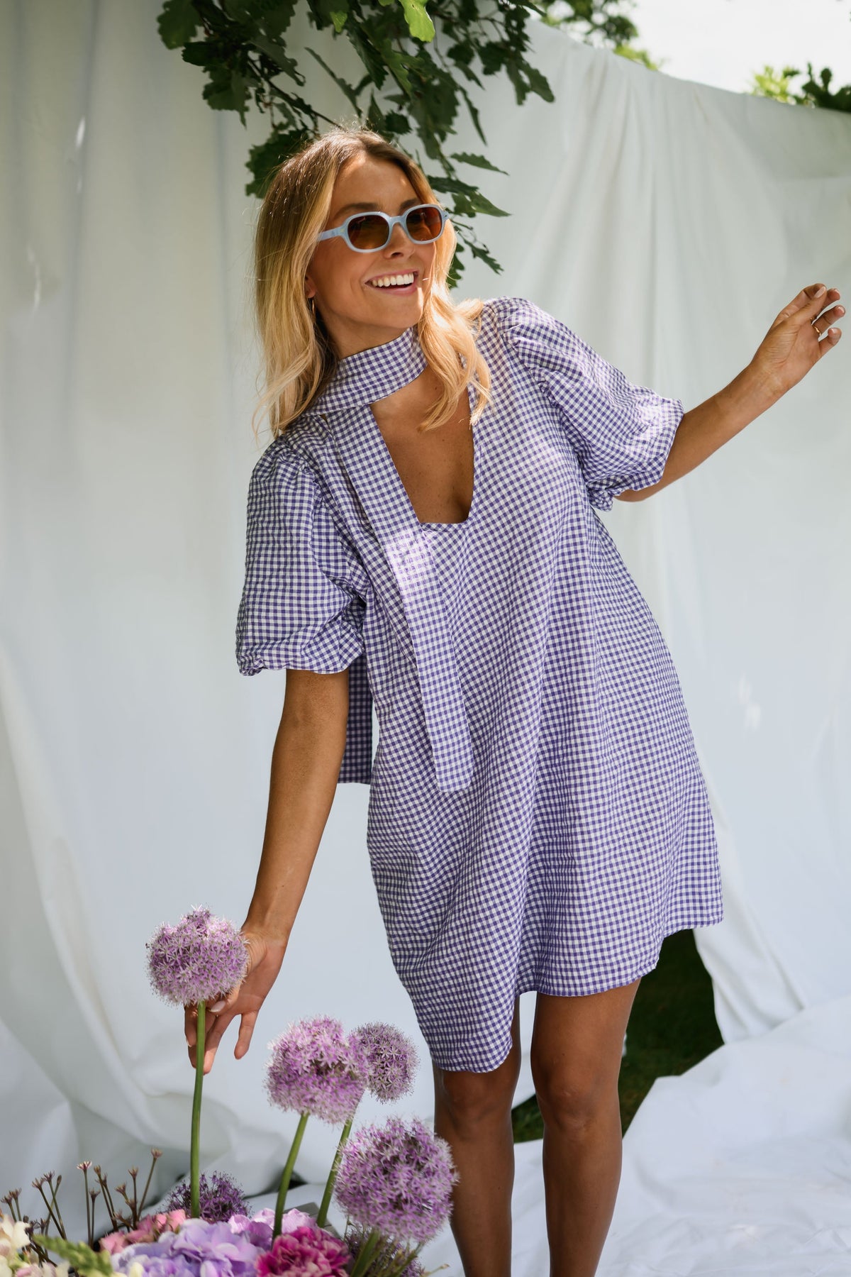 Robe fluide courte col V portée par une femme, silhouette entière, drapés blancs, lunettes