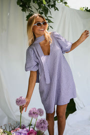 Robe fluide courte col V portée par une femme, silhouette entière, drapés blancs, lunettes