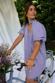 Robe fluide courte col V portée par une femme, vue de trois-quarts, vélo, main sur le guidon