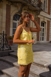 Robe courte à paillettes jaune portée par une femme, silhouette entière, escalier, balustrade