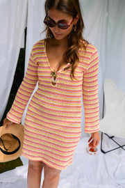 Robe courte en crochet portée par une femme, vue de trois-quarts, chapeau à la main, drapés