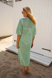 Robe en maille ajourée portée par une femme, vue de dos, sable, cabine