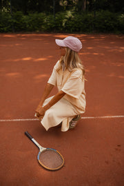 Robe longue effet pull portée par une femme, assise, accroupie, raquette