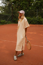 Robe longue effet pull portée par une femme, silhouette entière, casquette rose, raquette