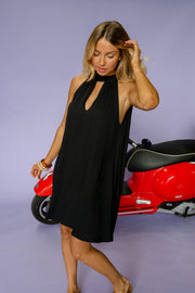 Robe courte dos ouvert noire portée par une femme, vue de trois-quarts, scooter rouge