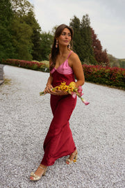 Robe longue en soie décolletée portée par une femme, en marchant, haie, bouquet