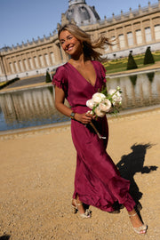 Robe longue en soie cache-cœur portée par une femme, vue de trois-quarts, bouquet blanc, château