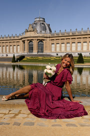 Robe longue en soie cache-cœur portée par une femme, assise, bouquet, jupe étalée