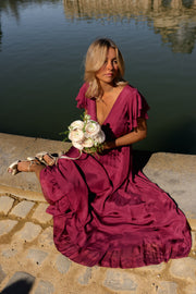 Robe longue en soie cache-cœur portée par une femme, silhouette entière, jupe étalée, bouquet