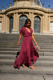 Robe longue en soie cache-cœur portée par une femme, silhouette entière, escalier, façade à colonnes