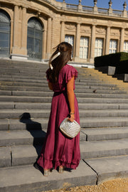 Robe longue en soie cache-cœur portée par une femme, vue de dos, escalier, sac