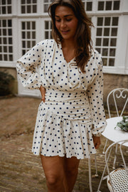 Robe cache-cœur à pois portée par une femme, vue de trois-quarts, cheveux bruns, jupe volantée