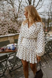 Robe cache-cœur à pois portée par une femme, vue de trois-quarts, terrasse, table dressée