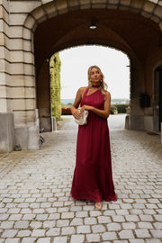 Robe longue en soie asymétrique portée par une femme, silhouette entière, arche en pierre, robe fluide