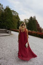 Robe longue en soie asymétrique portée par une femme, silhouette entière, gravier, pochette