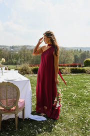 Robe longue en soie asymétrique portée par une femme, silhouette entière, table dressée, jardin