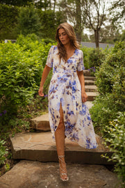 Robe portefeuille fleurie longue portée par une femme, silhouette entière, escalier en pierre, verdure