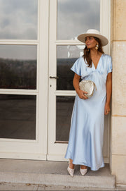 Robe satinée à manches courtes portée par une femme, silhouette entière, porte-fenêtre, chapeau de paille