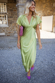 Robe satinée à col plissé portée par une femme, en marchant, gravier, pochette