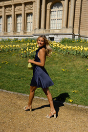 Robe fluide courte dos nu portée par une femme, silhouette entière, jonquilles, palais