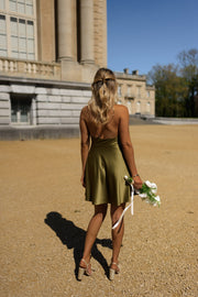 Robe courte satinée drapée portée par une femme, vue de dos croisé, bouquet